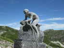 Montée : Colle Fauniera depuis Demonte, Commentaire : L'immanquable statue de Pantani. Entre la crête herbeuse et la statue, on devine le sommet du Mont Viso. 